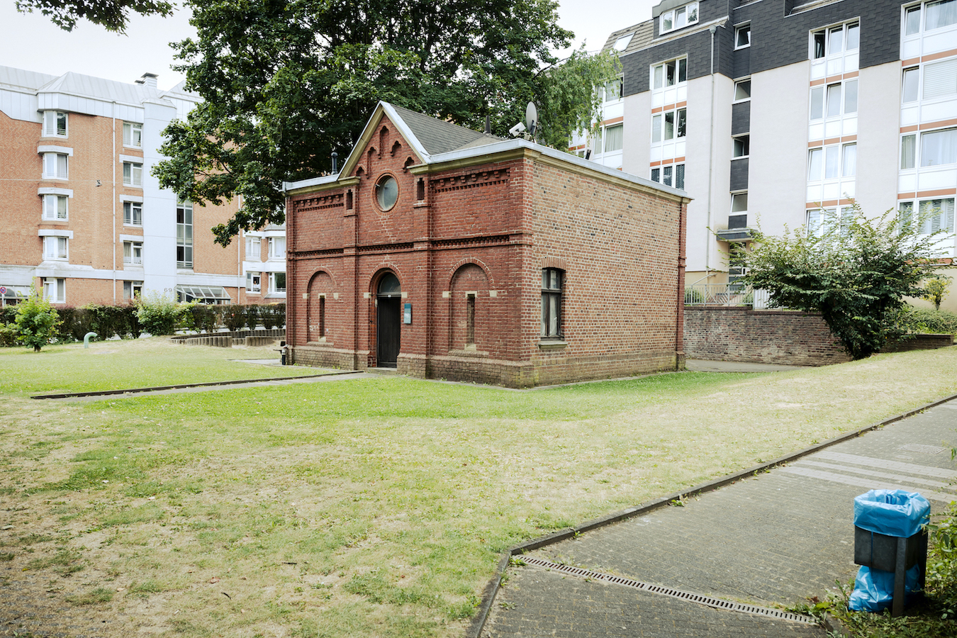 Das backsteinernde ehemalige Kutscherhaus mitten auf einer Wiese in einem Hinterhof